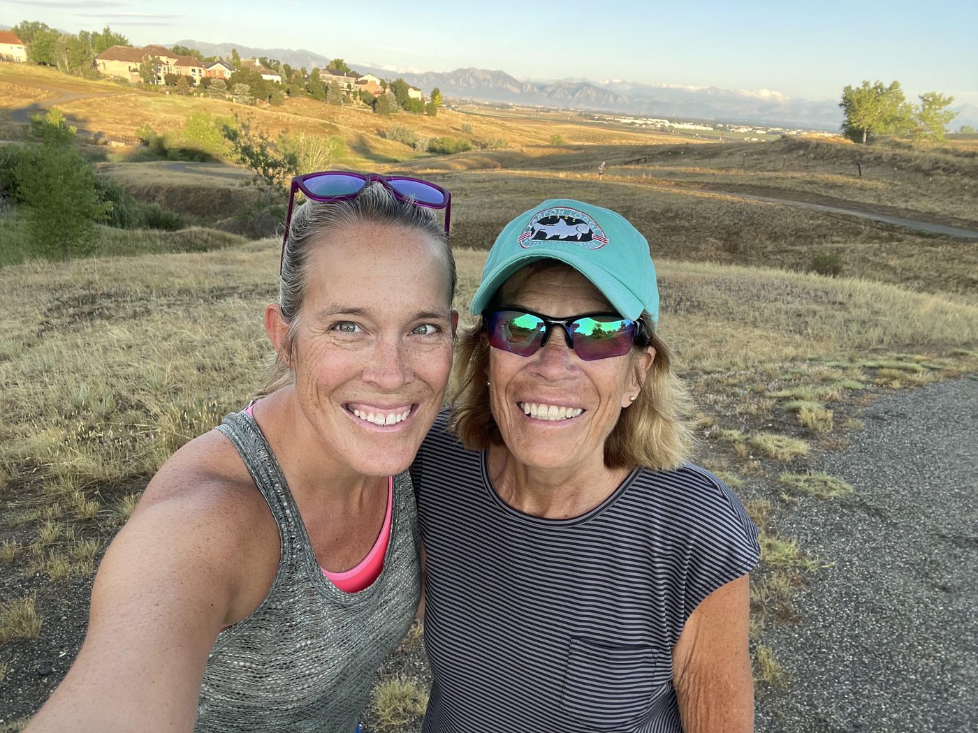 Jamie Dickinson and her mother side by side on a foothills trail at golden hour, both smiling, the Front Range behind them.